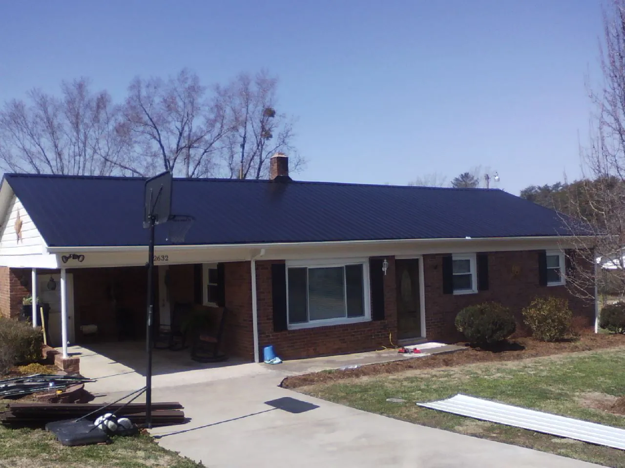 Finished dark blue metal roof on a brick ranch with a carport in Fincastle