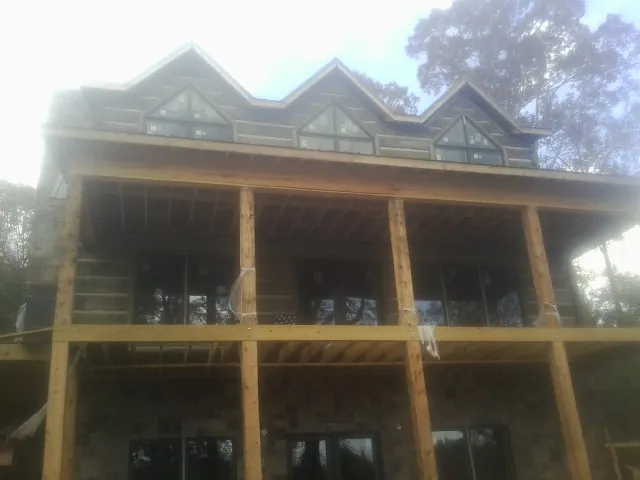 Dormers and porch framing on a large log home under construction — Roof Coating work by our crew in Fincastle