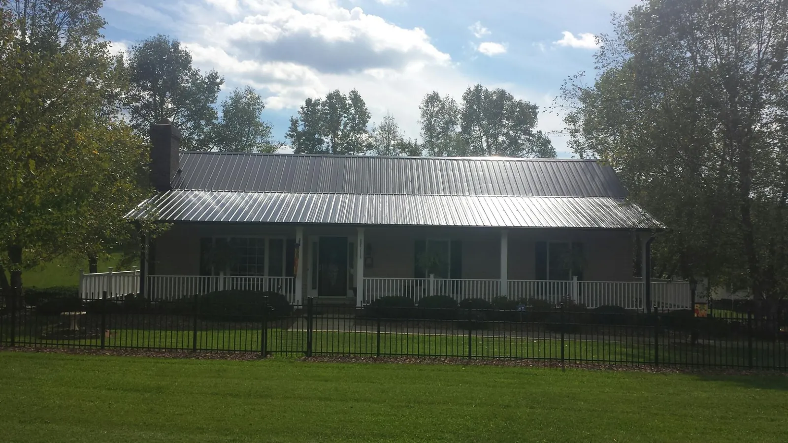 Gray metal roof on a brick ranch with a full width front porch — Gutter Guard Installation work by our crew in Fincastle