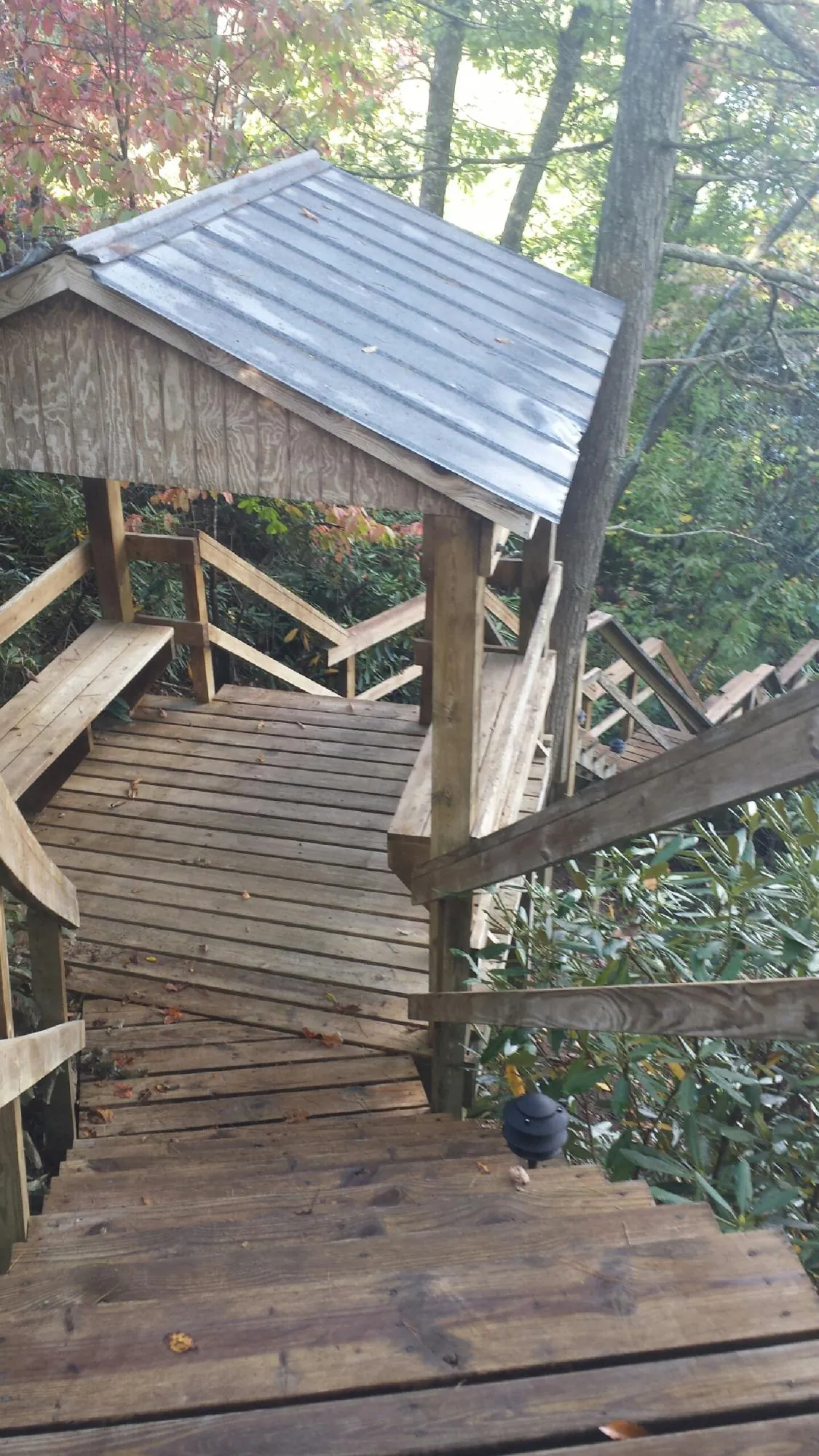 Metal roofed shelter over wooden steps on a wooded walkway — Skylight Repair & Installation work by our crew in Fincastle
