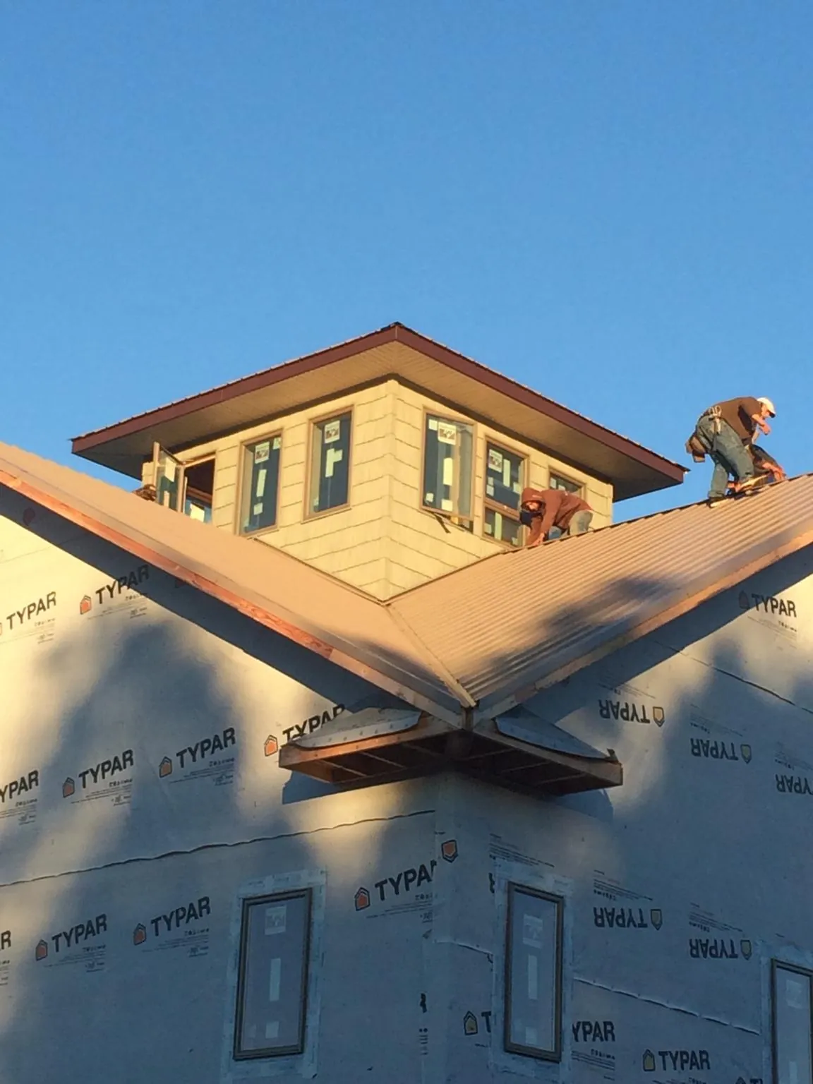 Roofers working around a rooftop cupola on a new metal roof at sunset — Roof Waterproofing in Fincastle by Roofing Brothers